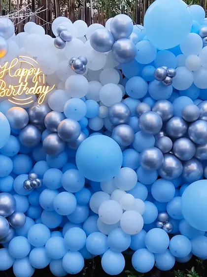 A cool and refreshing balloon wall in shades of blue, white, and silver. This 'Frozen' inspired backdrop with a 'Happy Birthday' neon sign is perfect for kids' parties or anyone who loves a winter wonderland theme.