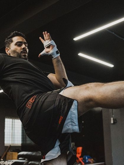 A fighter practices a high kick, showcasing the flexibility and balance developed through our training.