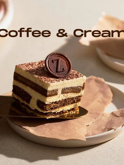 A slice of my Tiramisu being served. Topped with my signature chocolate 'Z' seal, this dessert combines coffee-soaked ladyfingers with creamy mascarpone mousse.