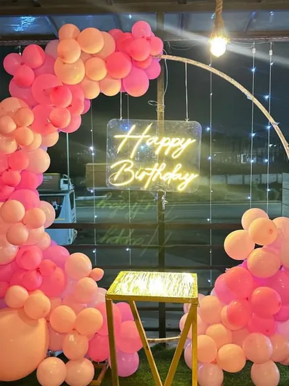 Perfect for a rooftop party, this half-ring balloon arch in shades of pink creates a beautiful frame against the evening sky. The 'Happy Birthday' neon sign ensures the setup looks great day or night.