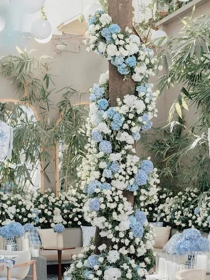 A tree trunk wrapped in a spiral of blue and white hydrangeas for Alanna Panday's baby shower, creating a stunning floral installation.