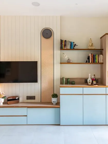 A full view of the TV and bar unit, showcasing the powder blue cabinetry and natural wood tones that create a light, contemporary feel.
