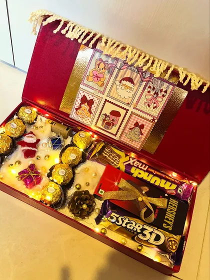 A beautiful red and gold Christmas box filled with chocolates and lit with fairy lights. The tassel fringe adds a touch of luxury.