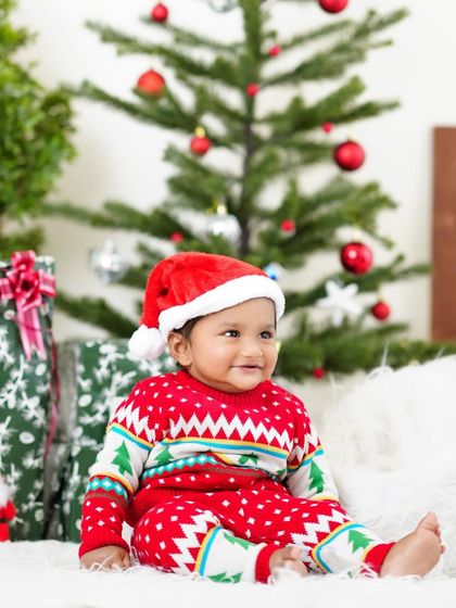 Santa's little helper! A baby boy in a Santa hat and Christmas sweater is all smiles for his holiday-themed photoshoot.
