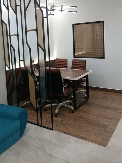 A view of the semi-private meeting area in the completed CA office. A decorative metal partition separates the space while maintaining visual connection, and the wooden flooring defines the zone.