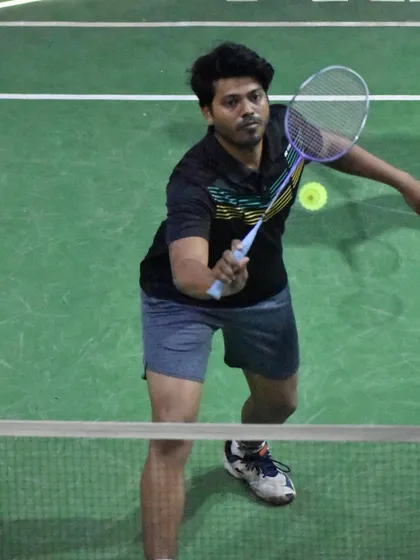 An adult player focused on a net shot, showcasing the concentration required for precise placement.