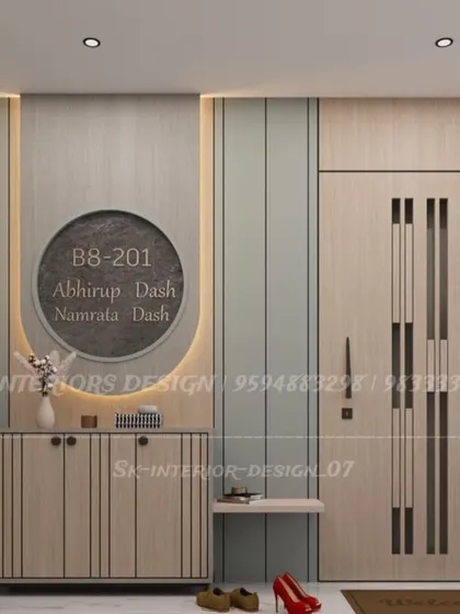 This foyer combines a custom nameplate with a console table for storage. The main door has a modern design with vertical slits, and the wall paneling adds texture.