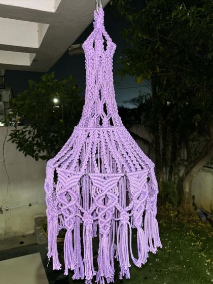 A lovely lavender macrame lantern hanging in the evening. These handmade lampshades are perfect for adding a soft, decorative light to your outdoor or indoor spaces.
