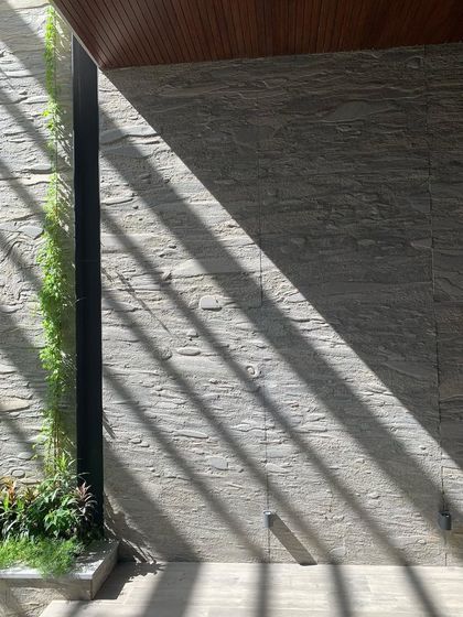 Magical light streams through a skylight at the T House, casting dramatic shadows on a textured stone wall. I design with light as a primary material, using it to animate spaces and reveal the beauty of surfaces.