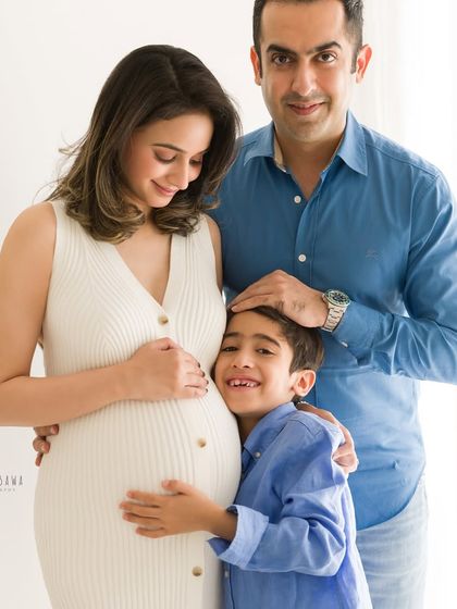 A tender family moment during a maternity shoot. The son’s happy embrace and the parents' gentle smiles create a portrait filled with love.