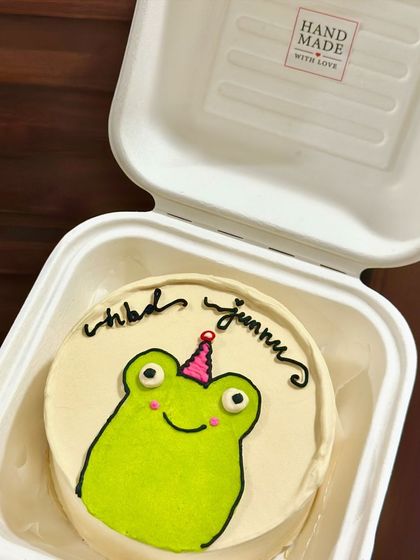 A cute frog with a party hat on a bento cake. This simple but charming illustration is perfect for a fun and lighthearted celebration.