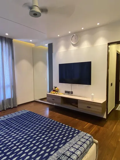 In this master bedroom, I designed a floating TV unit on a clean, white wall to maintain a minimalist and uncluttered feel. The warm wood flooring and soft recessed lighting create a cozy and relaxing environment, perfect for unwinding.
