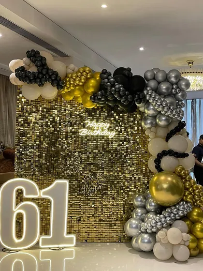 Another perspective of the glamorous 61st birthday setup. The organic balloon garland elegantly frames the golden shimmer wall, creating a rich and celebratory atmosphere for the milestone event.