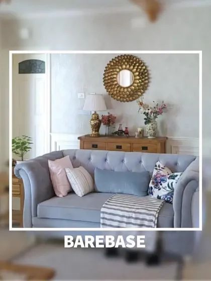 A snapshot of a cozy living room corner, where a classic sofa is styled with soft pillows against a backdrop of a gold sunburst mirror and wooden console.