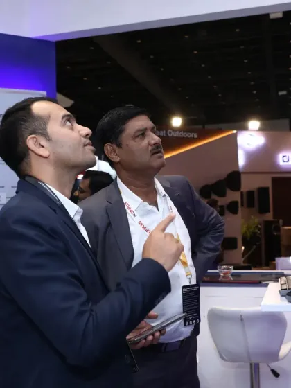 Two attendees look up at a display of mounted smart devices, evaluating their form factor and installation requirements for various projects.