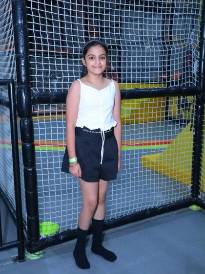 A young guest poses for a photo in our play area. The safety netting in the background shows how we've designed our space for worry-free fun.