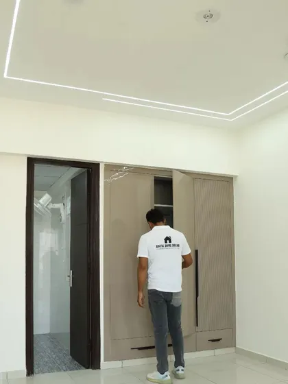 A completed bedroom at Nirala Estate with a simple wardrobe and a unique arched wall design.