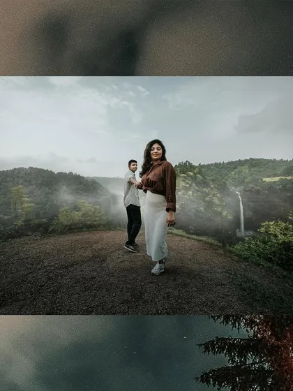 A wide, panoramic-style shot of a couple on a hilltop, with a misty valley and waterfall creating a breathtaking pre-wedding backdrop.