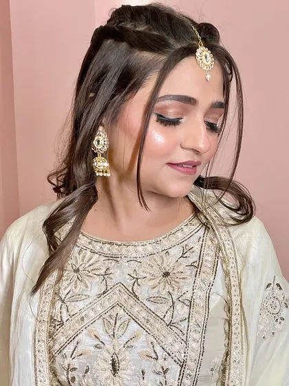 A subtle and elegant party makeup look. The off-white suit is paired with a soft smokey eye and a braided hairstyle.
