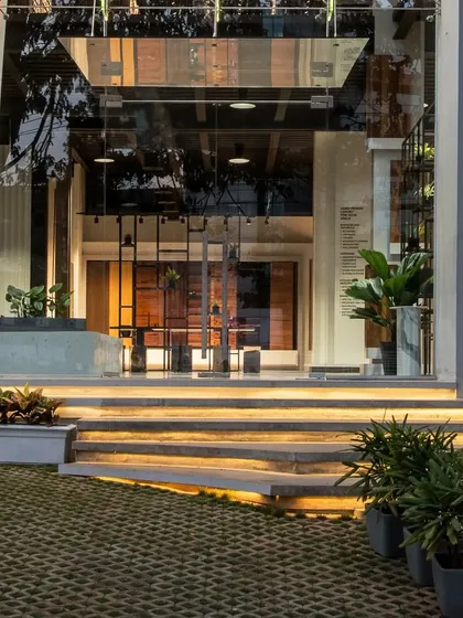 The entrance of a modern commercial building, featuring illuminated steps and a glass facade that offers a glimpse into the sophisticated interior.
