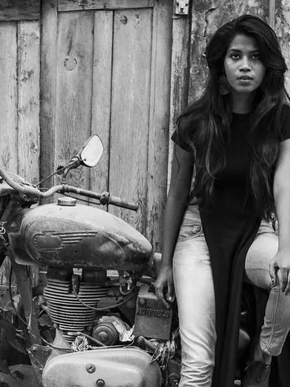A woman sitting on a vintage motorcycle. This black and white portrait is edgy and cool, with a strong sense of attitude.