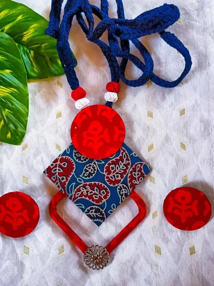 Another view of the mixed-print necklace, showing the combination of blue Kalamkari fabric and the bold red geometric elements.