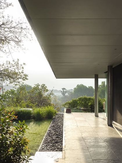 A covered veranda at the Vismaya museum blurs the line between the interior gallery and the exterior landscape. This transitional space offers visitors a place to rest and enjoy views of the surrounding greenery.