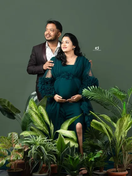 A confident and stylish pose surrounded by greenery. The dark teal gown stands out beautifully, creating a modern and chic pregnancy portrait for the expecting couple.