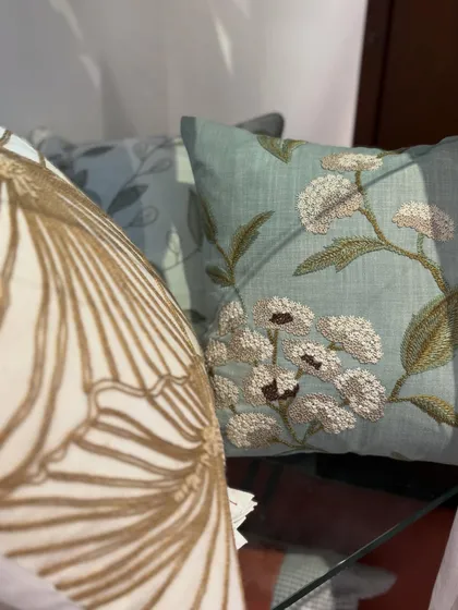 The sunlight catches the beautiful details of our embroidered cushions. This shot highlights the texture of the threadwork, from the bold, graphic pattern on the left to the delicate floral design on the right.