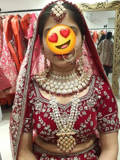 A happy client trying on her complete bridal look in our store. She paired a red velvet lehenga with a heavy Polki and pearl rani haar set.