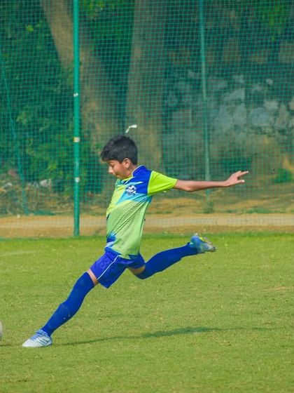 A young footballer strikes the ball cleanly, showcasing the kicking technique honed through our dedicated training programs.