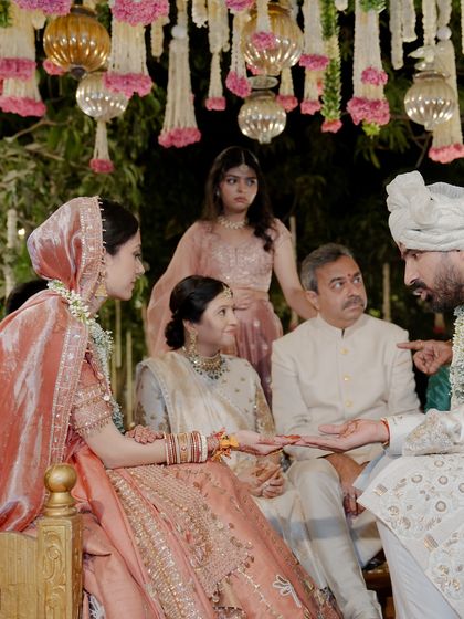 The parents of the groom seated beside the bride and groom during the wedding rituals. Their coordinated ivory outfits create a sense of unity and elegance for the entire family.