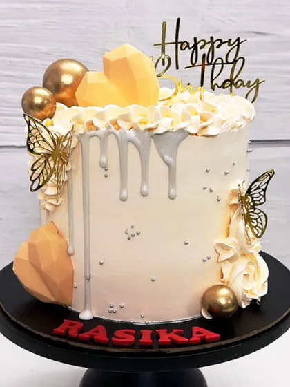 This classic birthday cake has it all: geometric hearts, golden butterflies, silver drip, and tiny pearls. It's a guaranteed hit.