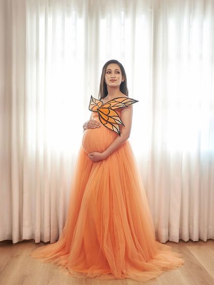 A whimsical and unique look. Our orange Isabella gown is styled with a beautiful, custom-made butterfly wing accessory.
