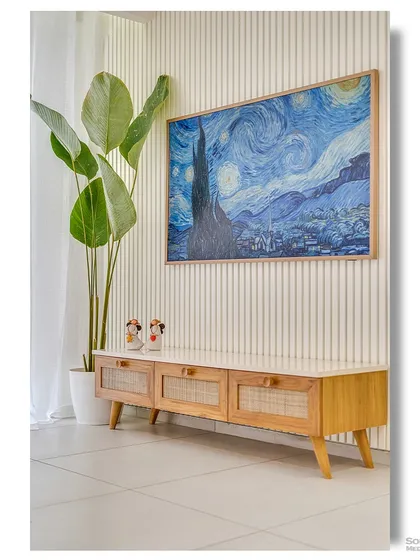 A minimalist TV console made of light wood with rattan-fronted drawers. A large print of Van Gogh's "Starry Night" adds a dramatic splash of color and artistry to the otherwise neutral space.