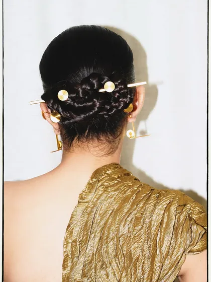 The details make the look. Here, the focus is on the intricate braided bun and custom hair accessories that completed this experimental outfit.