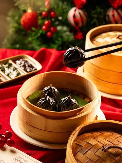 Black truffle dumplings for a Christmas menu. The festive red background contrasts beautifully with the dark, luxurious dumplings.