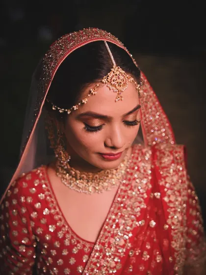 A classic bridal portrait focusing on the bride's exquisite jewelry and flawless makeup. This close-up captures the elegance and grace of a traditional Indian bride.