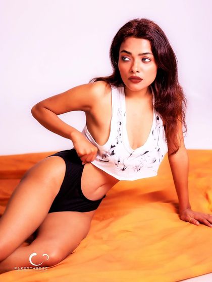 A relaxed and sensual portrait on a warm, orange fabric. The simple styling and her confident gaze create a powerful and intimate image.