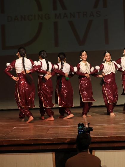 A behind-the-scenes view of our Bhangra performers on stage. This shot shows their synchronized formation from a unique angle, with the audience's perspective in the foreground.