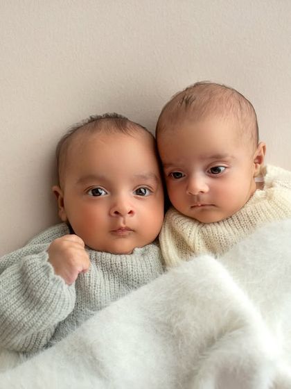 Another angle of the twins cuddled up. The simple background and soft blanket keep all the focus on their sweet faces.
