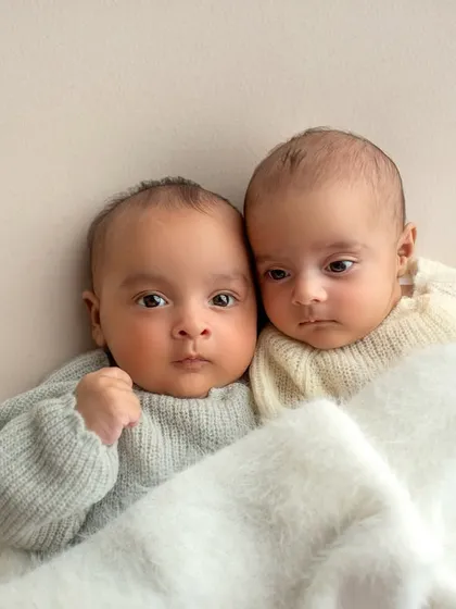Another angle of the twins cuddled up. The simple background and soft blanket keep all the focus on their sweet faces.