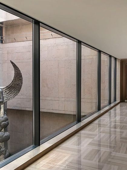 A view of the double-height courtyard from the second-floor corridor of 'The Layered Office'. The design provides various vantage points into this central space, which features a grand sculpture by Subodh Gupta.