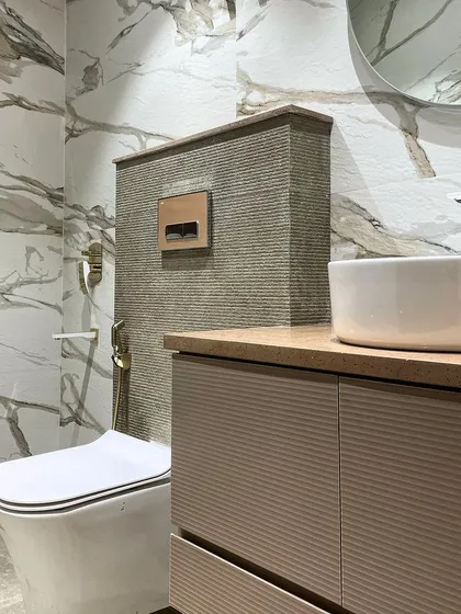 Another detail shot showing the floating vanity with a fluted finish and a simple vessel sink. The round mirror softens the clean lines of the space.
