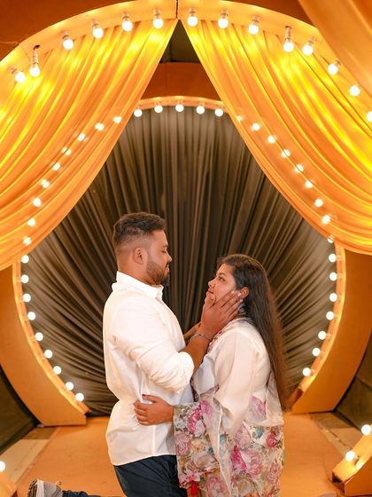 A romantic pose in front of a stage-like setup, with the couple framed by the golden curtains.