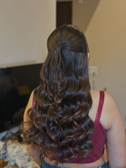 A trendy half-up style featuring a small, neat braid in the center, leading into a cascade of perfectly defined curls.