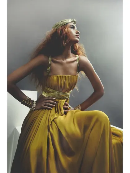 A lookbook image for designer Rudraksh Dwivedi. The styling of this golden gown is regal and powerful, with the model's pose accentuating the richness of the fabric.