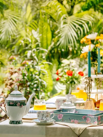 A wide shot of a tea set and serving tray from Vigneto, placed in a bright, sun-drenched garden. This image creates a strong feeling of a peaceful, leisurely afternoon.