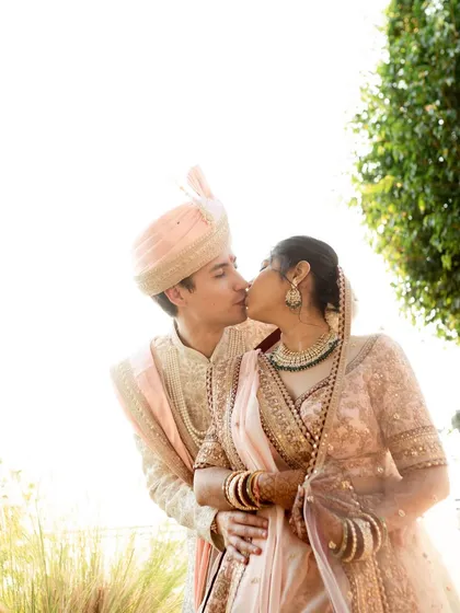 A romantic kiss shared by the couple, beautifully backlit by the sun. This photo has a dreamy, ethereal quality that perfectly captures the magic of their wedding day.