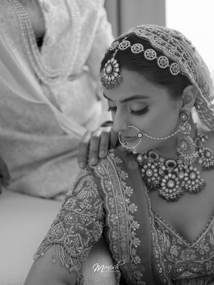 A close-up black and white portrait of the bride, capturing the intricate details of her jewelry and a quiet, emotional moment.
